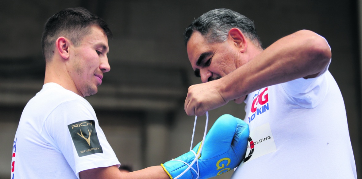 Trainer Abel Sanchez tying boxer's boxing gloves.
